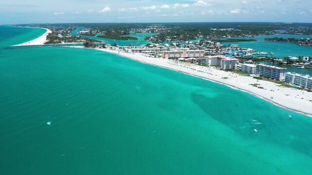 Buildings lining a broad, sandy beach with bright blue waters. Ideal for tourism and real estate projects.