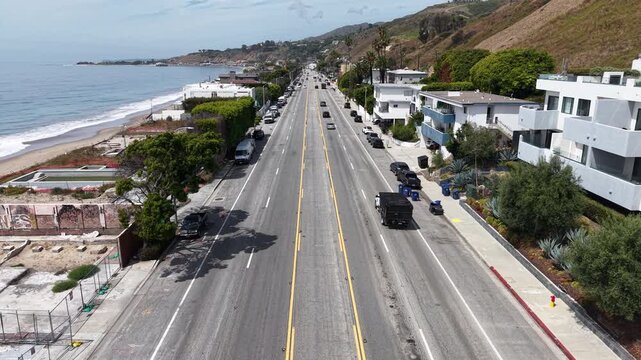 Cinematic daytime aerial drone footage captured just above the Pacific Coast Highway, featuring a slow forward dolly along the roadway as vehicles travel through the frame.
