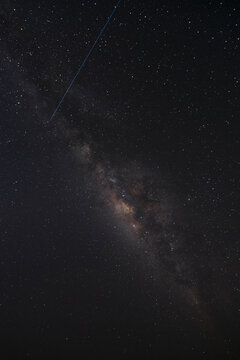 View of the Milky Way galaxy stretching across the dark night sky with a satellite streak in Socotra, Yemen.