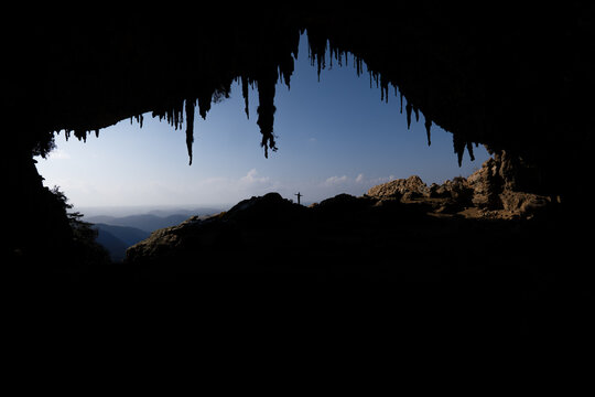 View of the silhouette of a person standing at the entrance of Hoq Cave with stalactites hanging from the ceiling in Socotra, Yemen.