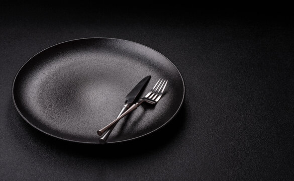 An empty ceramic round plate, kitchen utensils for a dinner table. An empty plate