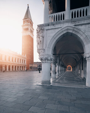 View of St. Mark's Campanile and the arches of Doge's Palace in an empty Piazza San Marco during sunrise Venice, Veneto, Italy.