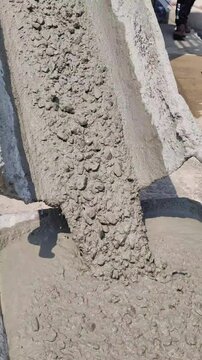 The liquid concrete is stopping flowing from the chute on the cement truck.