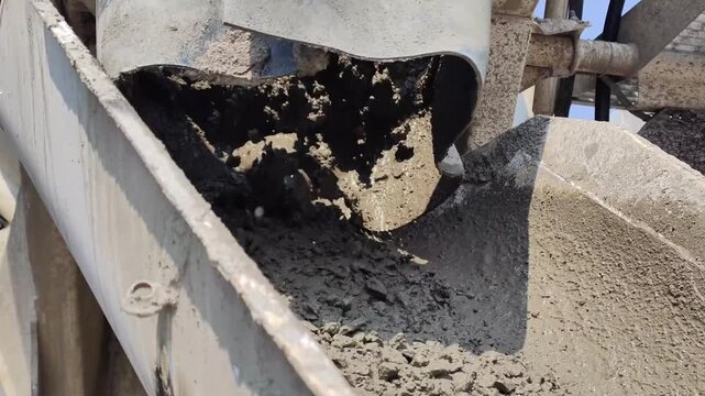 The liquid concrete is stopping flowing from the chute on the cement truck.