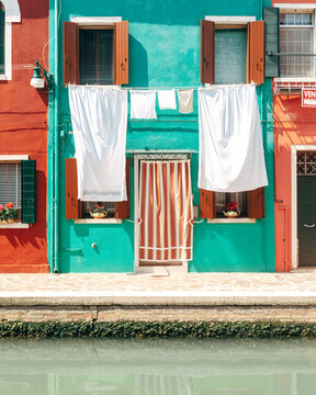 View of colorful houses with laundry hanging out to dry along a canal in Venice, Veneto, Italy.