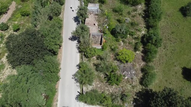 Aerial view of a large group of cyclists riding on a rural road in Mallorca during a bike race, Mediterranean landscape background.