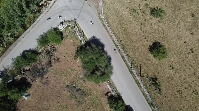 Aerial view of a large group of cyclists riding on a rural road in Mallorca during a bike race, Mediterranean landscape background.
