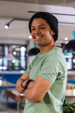 African American man standing smiling in coworking space wearing beanie bracelets green t-shirt
