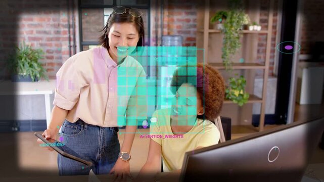 Standing woman pointing at monitor, initiating UI grid overlay, seated peer reviewing model in tech