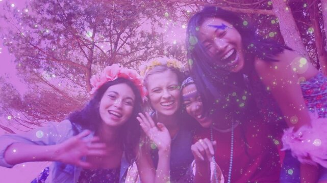 Low camera making 4 women leaning, waving, laughing with purple bokeh, crowns for creators