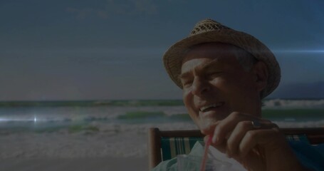 Fototapeta premium Sitting man sipping from plastic cup with red straw at shoreline, wearing straw hat, copy space