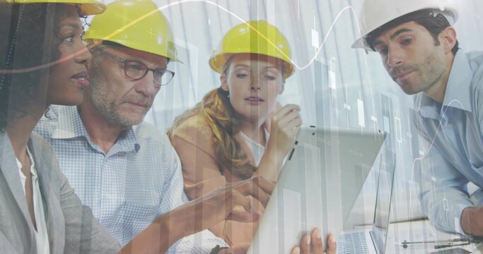 Discussing group of four professionals reviewing plans on laptop in site office, with hard hats