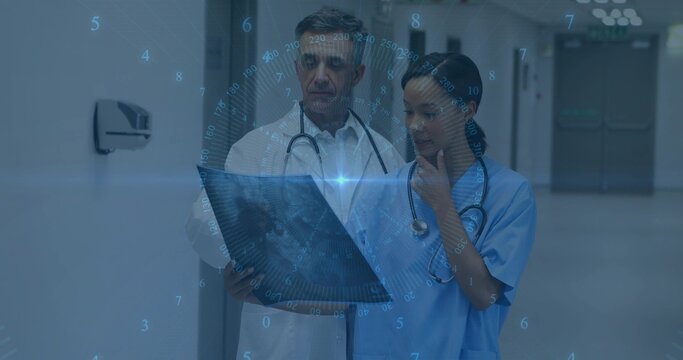 Examining doctor and nurse in blue scrubs studying X-ray in hospital hall, HUD overlay