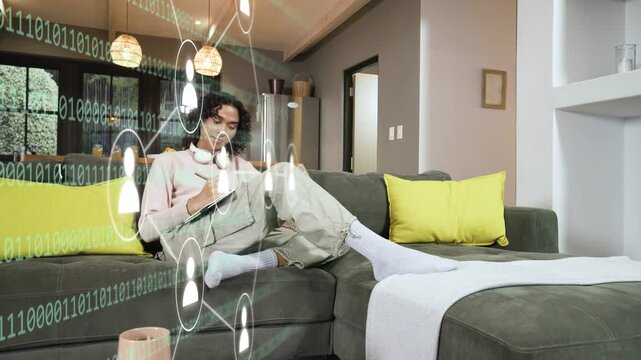 Nonbinary person writing on couch, tapping phone and causing binary nodes expanding for tech plans