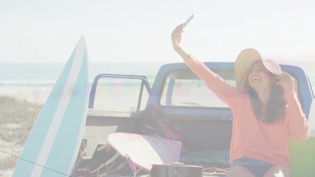 Woman sitting tailgate raising phone taking selfies adjusting hat overlays popping for travel post