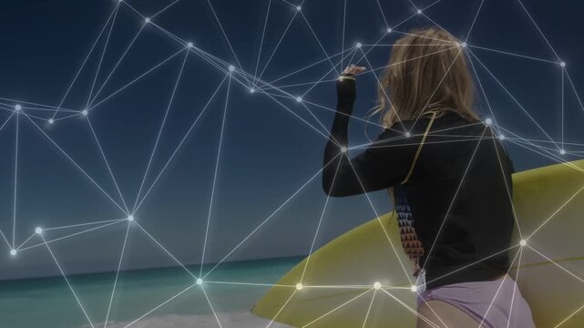 Woman shifting board and walking to sea, shading eyes, net overlay mapping waves preparing to surf