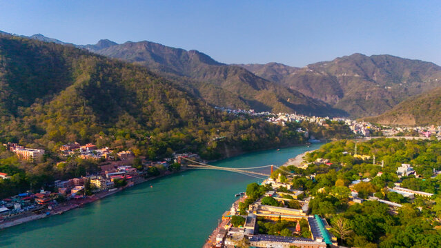 Aerial drone top view of the Ganga river flowing through Rishikesh with clear water, surrounding hills, and spiritual landscape