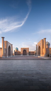 View of the historic Registan Square featuring ornate madrasahs with blue domes and intricate mosaic tilework under a soft morning sky in Samarkand, Samarqand Region, Uzbekistan.