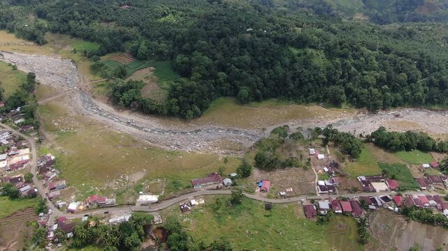 Agam, Indonesia - April 3rd 2026: Aerial Bird Eye View Drone Tracking Right over Salareh Aia Village, River, and Plantations Massive Boulders, Mud Debris, and Destroyed Agriculture