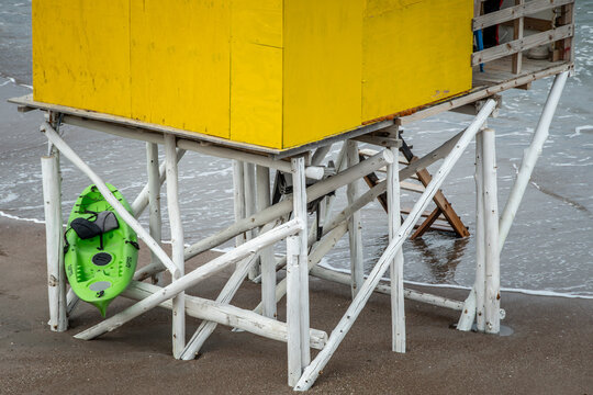 caseta del guardavidas en la playa de color amarillo para que sea visible , hecha de troncos y un bote de respaldo para alguna emergencia , se ve el mar sobre su base 