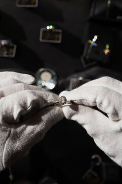 Expert checking gemstone silver ring with white gloves for condition.