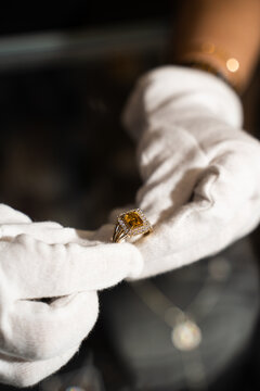Gloved hands checking silver ring with gemstones for craftsmanship details.