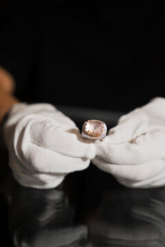 Jeweler analyzing silver ring with gemstones using gloves in studio.