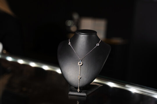 Silver jewelry piece styled on a black mannequin bust in a jewelry boutique.