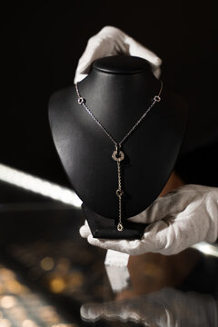 Silver jewelry piece displayed on black mannequin bust in jewelry boutique.