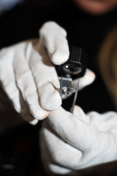 Gemologist inspects a diamond using tweezers and a loupe to evaluate clarity and cut quality.