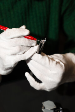 Gemologist marking diamond using red pen while holding it in tweezers.