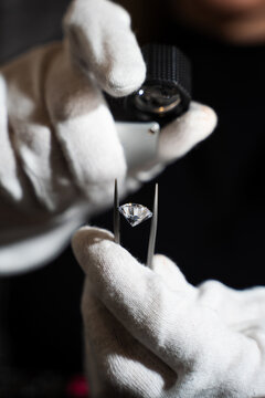 Close up of diamond examination with tweezers and loupe for quality assessment.