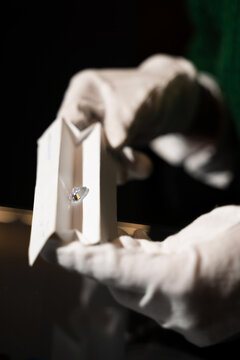 Gemologist using diamond sorting tray to assess clarity and brilliance under controlled conditions.