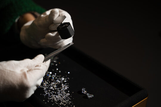 Close up of gemologist examining diamond using tweezers and loupe for grading clarity and cut.