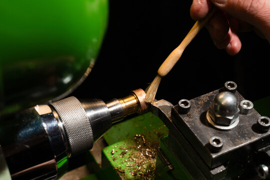 Jeweler applies cutting fluid with a brush before milling a ring on a precision machine.