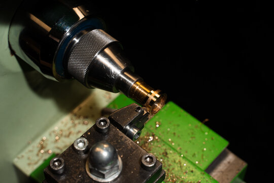 Close up of jeweler shaping gold ring on milling machine.