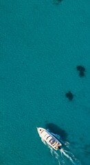 Fototapeta premium Minimalist Summer Background, A White Boat In A Vast Blue Sea, Top View, Central Empty Space For Text, Vertical Orientation