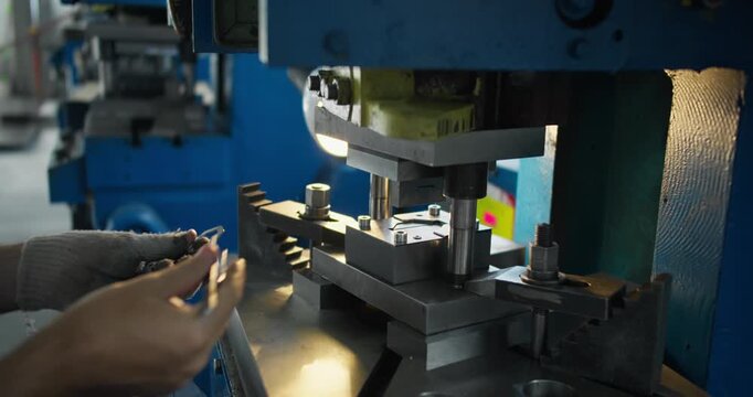 Close-up of hands at work with metal part and stamping die. Precision work and industrial manufacturing detail