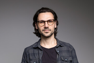 Obraz premium Smart professional man in glasses and plaid shirt with slight smile