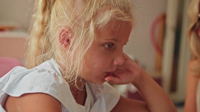 Tired preschool girl doing homework at home, close-up of focused face. Learning fatigue and early education overload