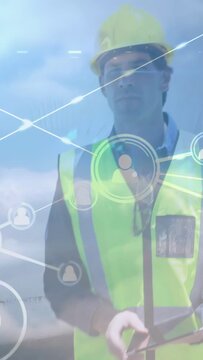 Vertical video: Helmeted engineer tapping tablet at worksite, HUD nodes expanding while monitoring