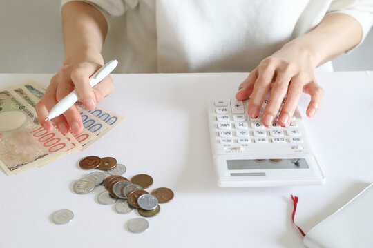 電卓でお金を計算する女性の手元