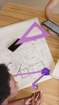 Vertical video: Designer inspecting 3D AR model as peer tilting tablet checking plan fit for design