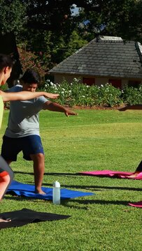Vertical video: Boy on blue mat shifting into side-bend, group holding triangle pose for fitness