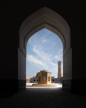 View of the Kalyan Mosque courtyard and the Kalyan Minaret through a large pointed archway in Bukhara, Bukhara Region, Uzbekistan.