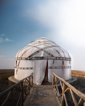 View of a traditional white yurt with decorative patterns and a wooden walkway in a desert landscape under a clear blue sky Bukhara, Bukhara Region, Uzbekistan.