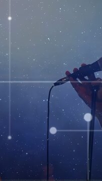 Vertical video: Male singer leaning into mic singing gripping mic grid stars floating in music haze