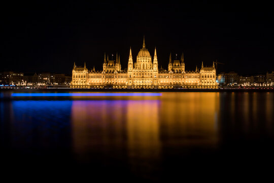View of the illuminated Hungarian Parliament Building reflecting in the dark waters of the Danube river at night Budapest, Hungary.