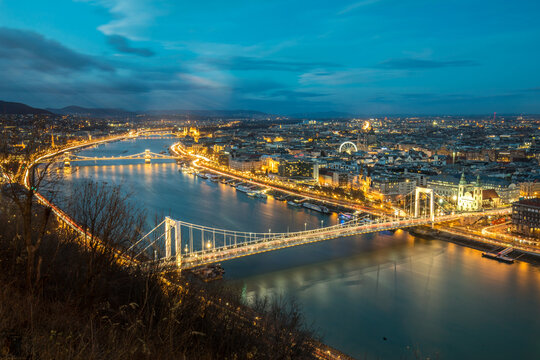 View of the illuminated Elisabeth Bridge and Chain Bridge spanning the Danube river with city lights at twilight Budapest, Hungary.