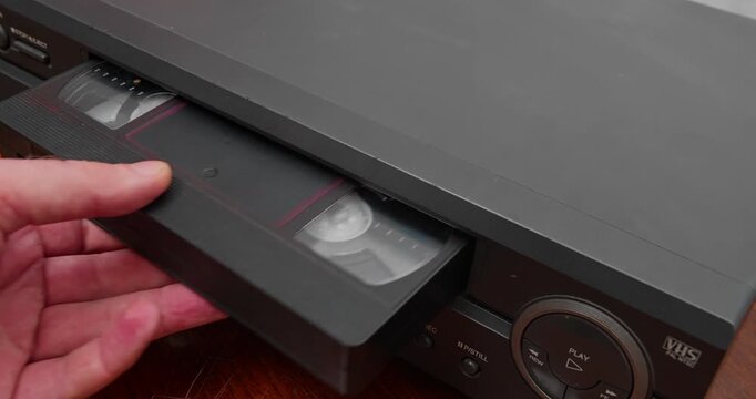 VHS tape partially ejected from VCR in close-up shot. Retro media device and pre-digital video technology